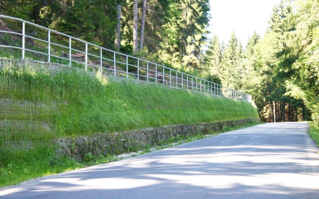 Výškové oddělení silnice a cyklostezky strmým svahem v Prášilech na Šumavě