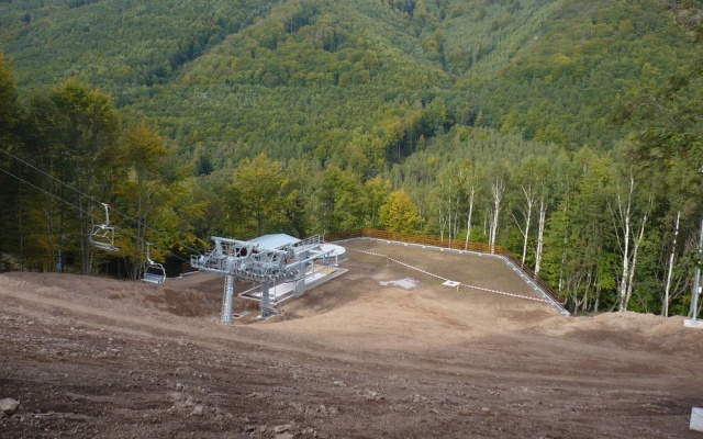 Opěrná zeď vyrovnávající strmý terén stanice lanové dráhy sjezdovky v Klínech