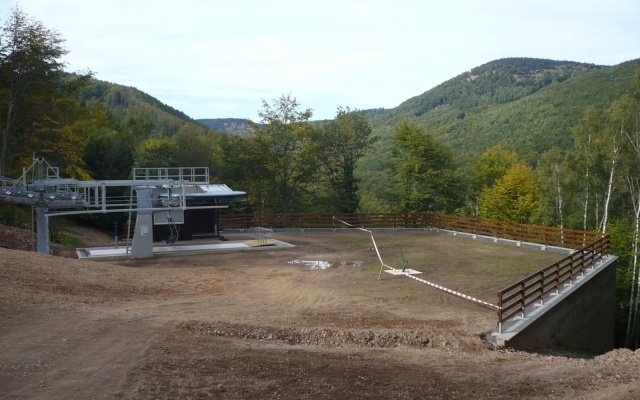 Opěrná zeď vyrovnávající strmý terén stanice lanové dráhy sjezdovky v Klínech